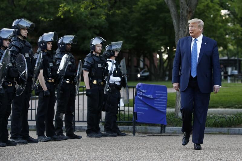President Donald Trump walks past police in Lafayette Park.jpeg